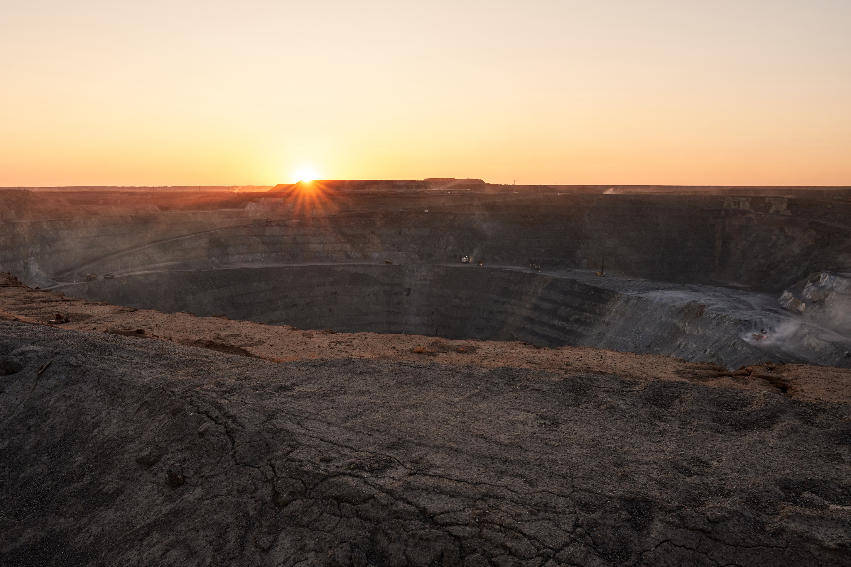 A picture of the sun setting over an open pit mine
