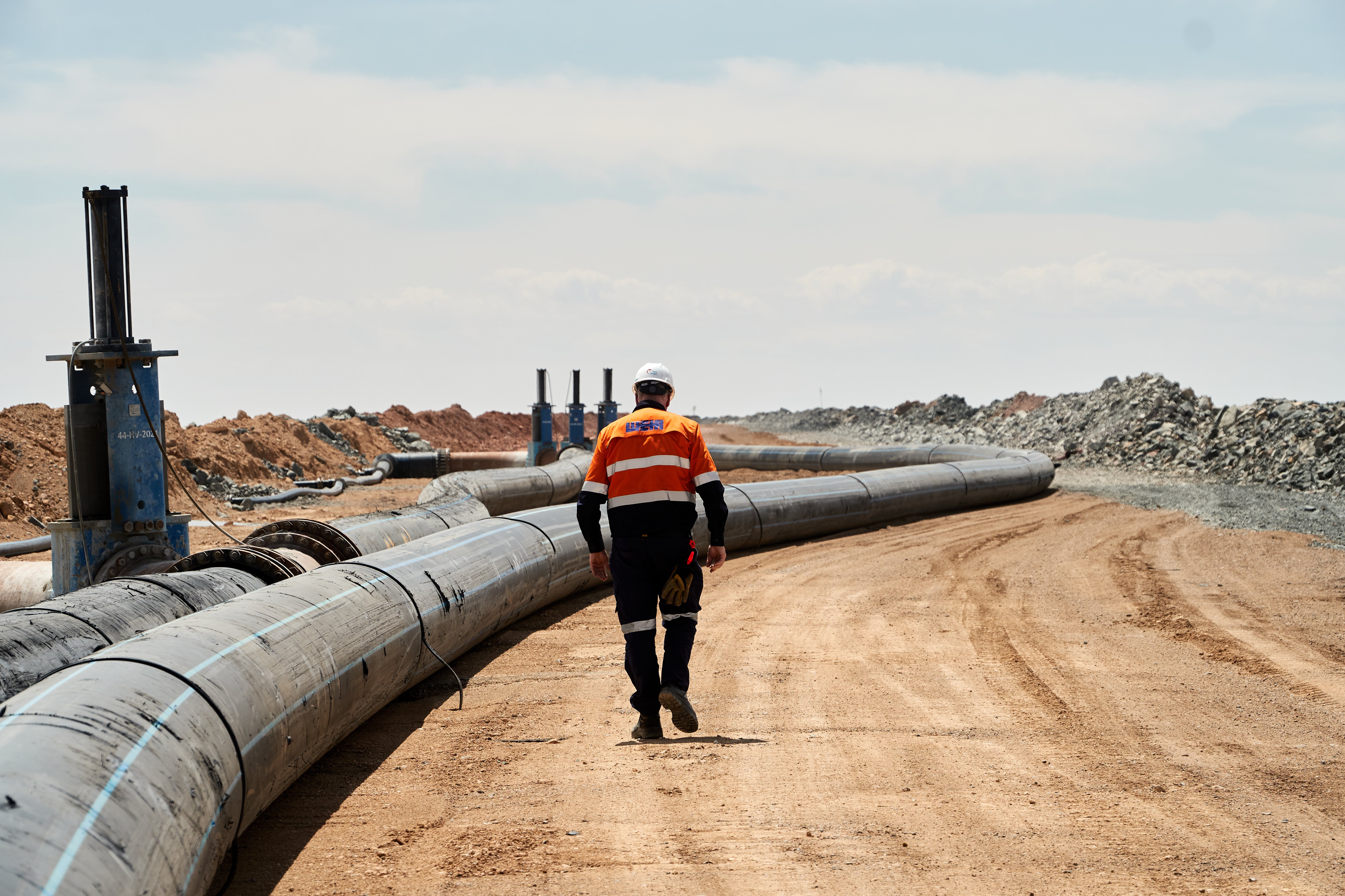 Weir employee walking along a tailings pipeline for inspection.